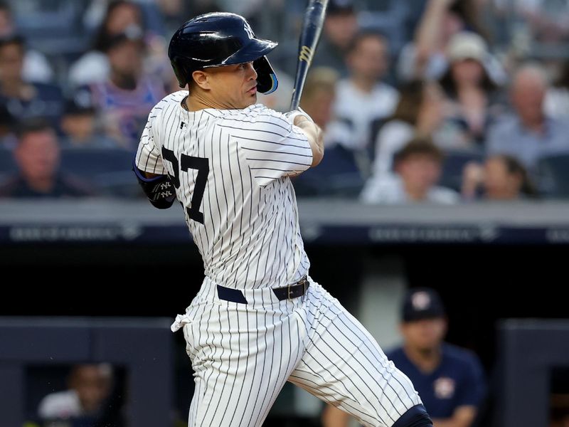 May 8, 2024; Bronx, New York, USA; New York Yankees designated hitter Giancarlo Stanton (27) follows through on a solo home run against the Houston Astros during the third inning at Yankee Stadium. Mandatory Credit: Brad Penner-USA TODAY Sports