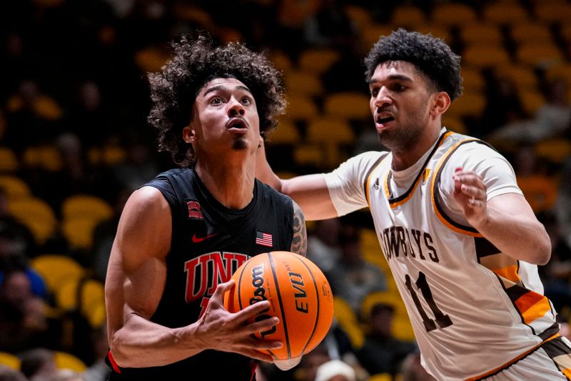 Feb 27, 2024; Laramie, Wyoming, USA; UNLV Runnin' Rebels guard Brooklyn Hicks (13) drives against Wyoming Cowboys guard Kael Combs (11) during the second half at Arena-Auditorium. Mandatory Credit: Troy Babbitt-USA TODAY Sports