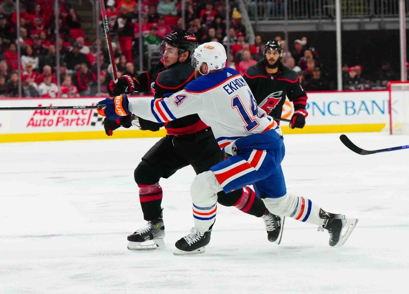 Nov 22, 2023; Raleigh, North Carolina, USA; Edmonton Oilers defenseman Mattias Ekholm (14) checks Carolina Hurricanes defenseman Dmitry Orlov (7) during the first period at PNC Arena. Mandatory Credit: James Guillory-USA TODAY Sports