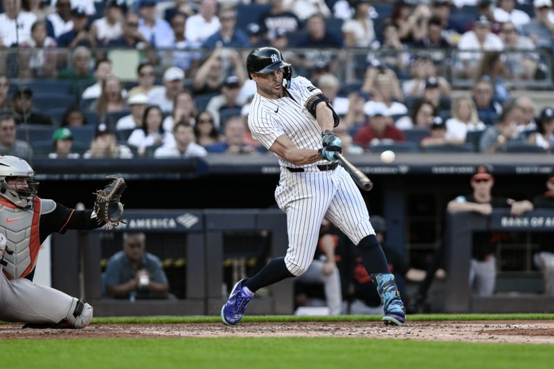 Sep 28, 2025; Bronx, New York, USA; New York Yankees designated hitter Giancarlo Stanton (27) hits an RBI single against the Baltimore Orioles during the fourth inning at Yankee Stadium. Mandatory Credit: John Jones-Imagn Images