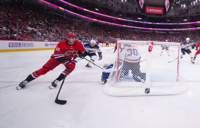 Nov 17, 2024; Raleigh, North Carolina, USA;  Carolina Hurricanes center Martin Necas (88) skates with the puck behind the St. Louis Blues net during the third period at Lenovo Center. Mandatory Credit: James Guillory-Imagn Images