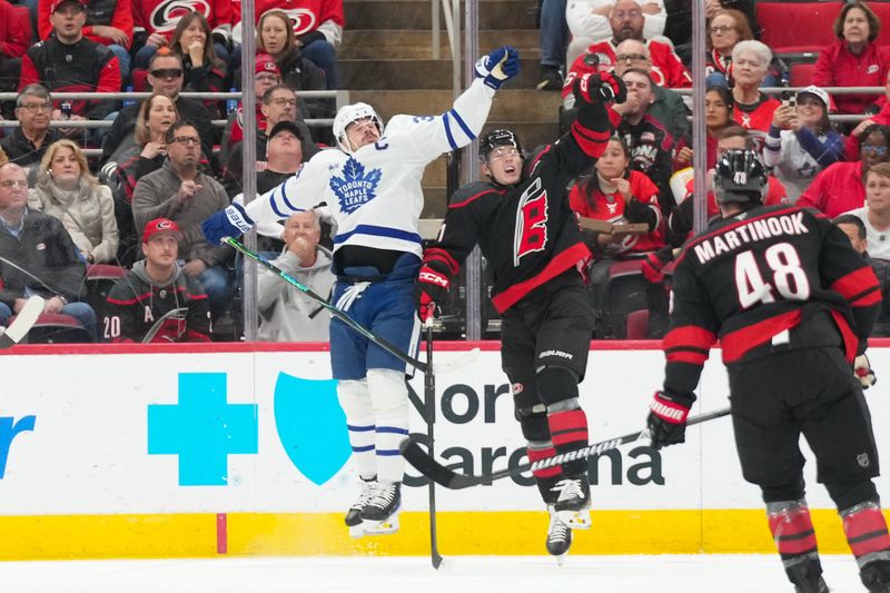 Dec 4, 2025; Raleigh, North Carolina, USA; Toronto Maple Leafs center Auston Matthews (34) and Carolina Hurricanes defenseman Alexander Nikishin (21) leap for the puck during the first period at Lenovo Center. Mandatory Credit: James Guillory-Imagn Images Dec 4, 2025; Raleigh, North Carolina, USA; Toronto Maple Leafs center Auston Matthews (34) and Carolina Hurricanes defenseman Alexander Nikishin (21) leap for the puck during the first period at Lenovo Center. Mandatory Credit: James Guillory-Imagn Images