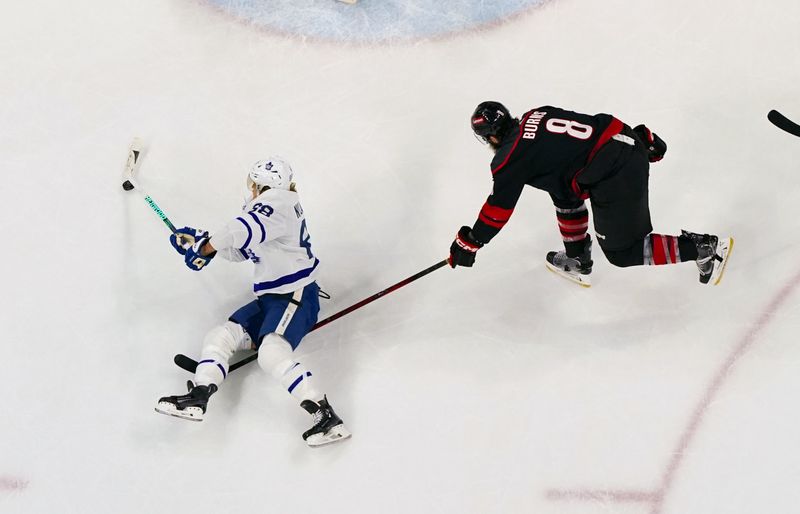 Mar 24, 2024; Raleigh, North Carolina, USA;  Toronto Maple Leafs right wing William Nylander (88) tries to get the shot away against Carolina Hurricanes defenseman Brent Burns (8) during the third period at PNC Arena. Mandatory Credit: James Guillory-USA TODAY Sports