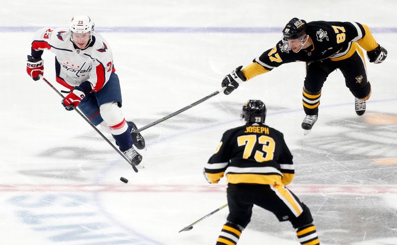 Mar 7, 2024; Pittsburgh, Pennsylvania, USA; Washington Capitals center Michael Sgarbossa (23) moves the puck against Pittsburgh Penguins center Sidney Crosby (87) and defenseman Pierre-Olivier Joseph (73) during the third period at PPG Paints Arena. The Capitals shutout the Penguins 6-0. Mandatory Credit: Charles LeClaire-USA TODAY Sports