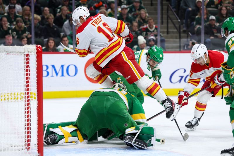 Nov 9, 2025; Saint Paul, Minnesota, USA; Calgary Flames center Morgan Frost (16) jumps over Minnesota Wild goaltender Jesper Wallstedt (30) during the third period at Grand Casino Arena. Mandatory Credit: Matt Krohn-Imagn Images