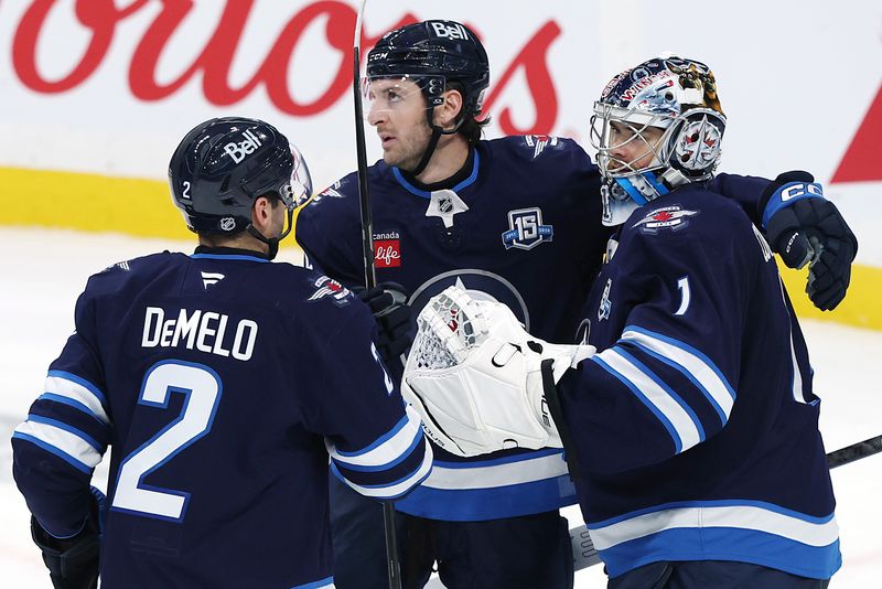 Nov 1, 2025; Winnipeg, Manitoba, CAN; Winnipeg Jets defenseman Dylan Demelo (2), defenseman Colin Miller (6) and goaltender Eric Comrie (1) celebrate their victory against the Pittsburgh Penguins at Canada Life Centre. Mandatory Credit: James Carey Lauder-Imagn Images
