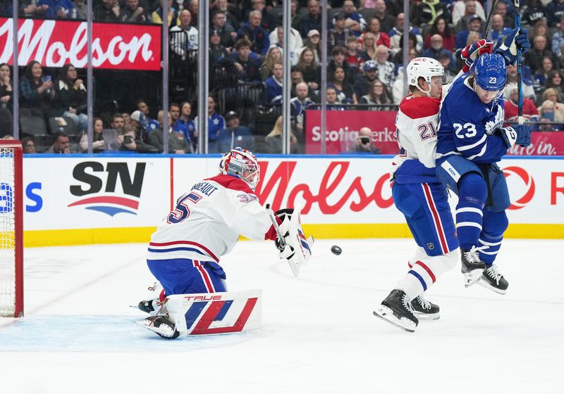 Nov 9, 2024; Toronto, Ontario, CAN; Toronto Maple Leafs left wing Matthew Knies (23) battles for the puck with Montreal Canadiens defenseman Kaiden Guhle (21) in front of  goaltender Sam Montembeault (35) during the first period at Scotiabank Arena. Mandatory Credit: Nick Turchiaro-Imagn Images