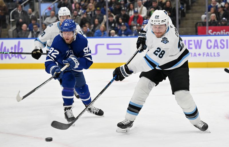 Nov 24, 2024; Toronto, Ontario, CAN;  Utah Hockey Club defenseman Ian Cole (28) shoots the puck past Toronto Maple Leafs forward Alexander Nylander (92) in the first period at Scotiabank Arena. Mandatory Credit: Dan Hamilton-Imagn Images