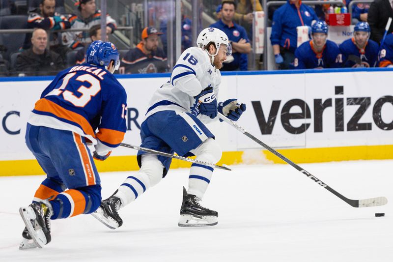 Dec 11, 2023; Elmont, New York, USA; Toronto Maple Leafs center Noah Gregor (18) moves the puck up ice while New York Islanders center Mathew Barzal (13) pursues during the second period at UBS Arena. Mandatory Credit: Thomas Salus-USA TODAY Sports