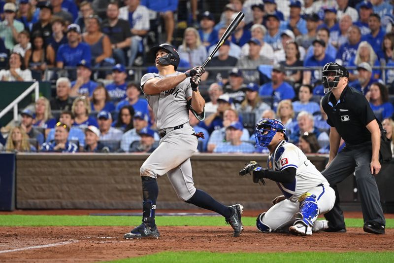 Oct 9, 2024; Kansas City, Missouri, USA; New York Yankees designated hitter Giancarlo Stanton (27) hits a home run in the eighth inning against the Kansas City Royals during game three of the NLDS for the 2024 MLB Playoffs at Kauffman Stadium. Mandatory Credit: Peter Aiken-Imagn Images