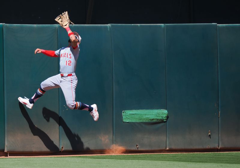 Jul 4, 2024; Oakland, California, USA; Los Angeles Angels center fielder Kevin Pillar (12) jumps up but is unable to catch the ball for an Oakland Athletics home run during the eighth inning at Oakland-Alameda County Coliseum. Mandatory Credit: Kelley L Cox-USA TODAY Sports