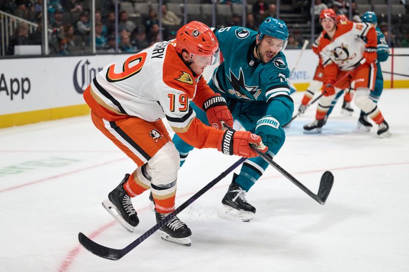 Oct 1, 2025; San Jose, California, USA; Anaheim Ducks right wing Troy Terry (19) plays the puck against San Jose Sharks defenseman Vincent Desharnais (5) during the first period at SAP Center at San Jose. Mandatory Credit: Robert Edwards-Imagn Images