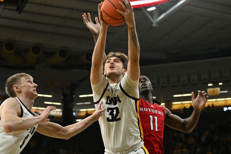 Jan 6, 2024; Iowa City, Iowa, USA; Iowa Hawkeyes forward Owen Freeman (32) grabs a rebound in front of guard Josh Dix (4) and Rutgers Scarlet Knights center Clifford Omoruyi (11) during the first half at Carver-Hawkeye Arena. Mandatory Credit: Jeffrey Becker-USA TODAY Sports