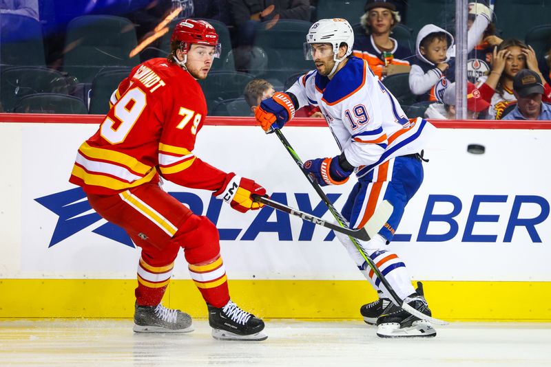 Sep 23, 2024; Calgary, Alberta, CAN; Calgary Flames right wing Cole Schwindt (79) and Edmonton Oilers center Adam Henrique (19) battles for the puck during the second period at Scotiabank Saddledome. Mandatory Credit: Sergei Belski-Imagn Images