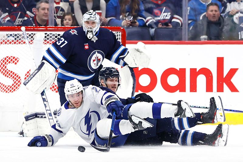 Jan 2, 2024; Winnipeg, Manitoba, CAN; A fallen Tampa Bay Lightning center Brayden Point (21) scrambles for the puck in front of Winnipeg Jets goaltender Connor Hellebuyck (37) in the second period at Canada Life Centre. Mandatory Credit: James Carey Lauder-USA TODAY Sports