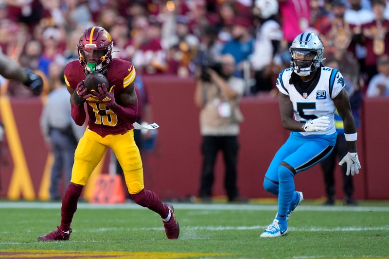 Washington Commanders cornerback Emmanuel Forbes Jr. (13) intercepts a pass in front of Carolina Panthers wide receiver Diontae Johnson (5) during the first half of an NFL football game, Sunday, Oct. 20, 2024, in Landover, Md. (AP Photo/Stephanie Scarbrough)