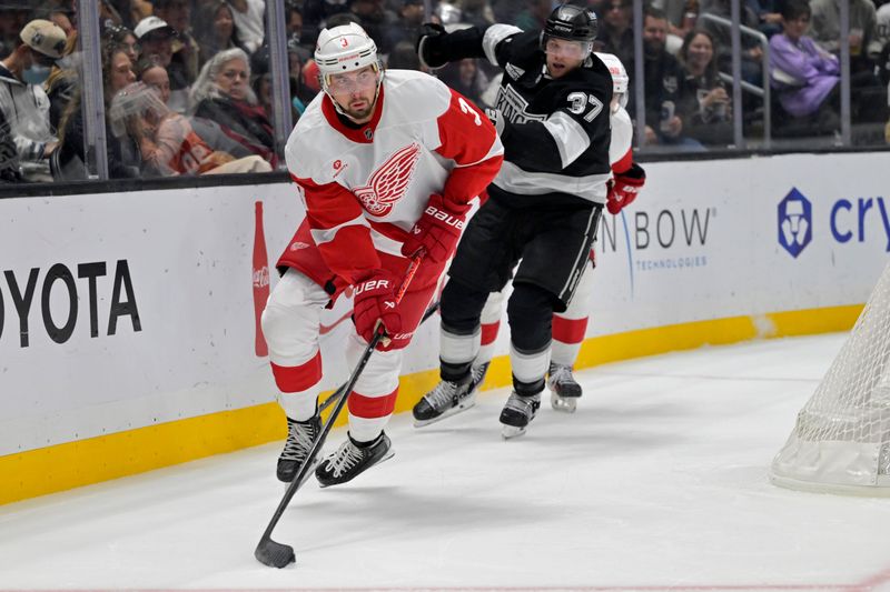 Nov 16, 2024; Los Angeles, California, USA; Detroit Red Wings defenseman Justin Holl (3) controls the puck away from Los Angeles Kings left wing Warren Foegele (37) in the second period at Crypto.com Arena. Mandatory Credit: Jayne Kamin-Oncea-Imagn Images