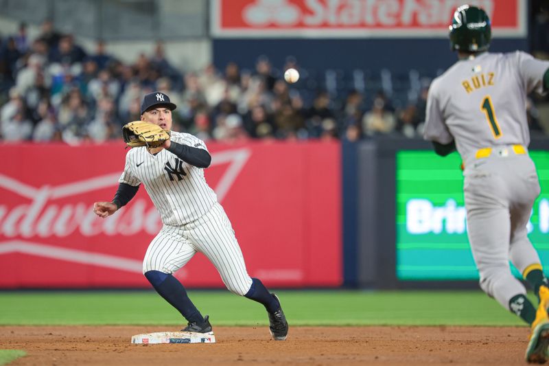 Apr 25, 2024; Bronx, New York, USA; New York Yankees shortstop Anthony Volpe (11) forces out Oakland Athletics left fielder Esteury Ruiz (1) at second base at Yankee Stadium. Mandatory Credit: Vincent Carchietta-USA TODAY Sports