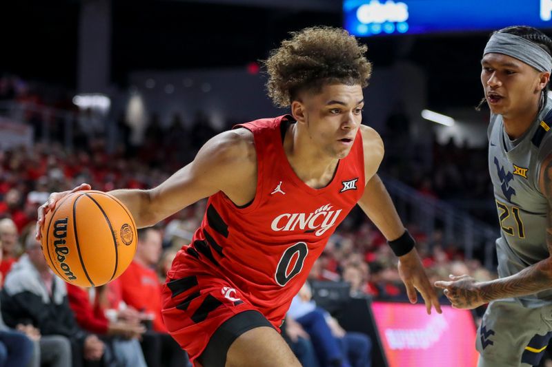 Mar 9, 2024; Cincinnati, Ohio, USA; Cincinnati Bearcats guard Dan Skillings Jr. (0) dribbles against West Virginia Mountaineers guard RaeQuan Battle (21) in the first half at Fifth Third Arena. Mandatory Credit: Katie Stratman-USA TODAY Sports