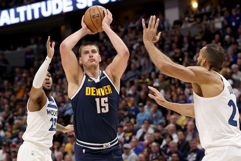 DENVER, COLORADO - APRIL 10: Nikola Jokic #15 of the Denver Nuggets goes to the basket against Monte Morris #23 and Rudy Gobert #27 of the Minnesota Timberwolves during the first quarter at Ball Arena on April 10, 2024 in Denver, Colorado. NOTE TO USER: User expressly acknowledges and agrees that, by downloading and or using this photograph, User is consenting to the terms and conditions of the Getty Images License Agreement.  (Photo by Matthew Stockman/Getty Images)