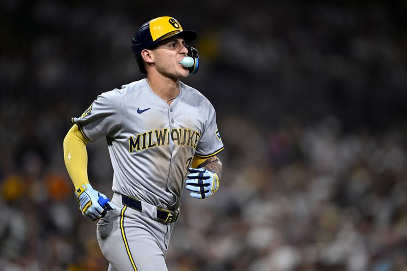 Jun 20, 2024; San Diego, California, USA; Milwaukee Brewers third baseman Joey Ortiz (3) blows a bubble-gum bubble while running to first base after a walk during the eighth inning against the San Diego Padres at Petco Park. Mandatory Credit: Orlando Ramirez-USA TODAY Sports