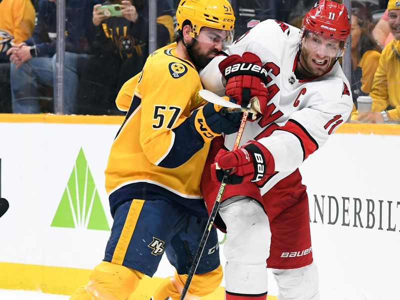 Dec 27, 2023; Nashville, Tennessee, USA; Carolina Hurricanes center Jordan Staal (11) passes the puck as he is defended by Nashville Predators defenseman Dante Fabbro (57) during the second period at Bridgestone Arena. Mandatory Credit: Christopher Hanewinckel-USA TODAY Sports