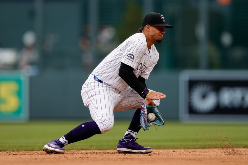 Apr 10, 2024; Denver, Colorado, USA; Colorado Rockies shortstop Ezequiel Tovar (14) fields the ball in the fifth inning against the Arizona Diamondbacks at Coors Field. Mandatory Credit: Isaiah J. Downing-USA TODAY Sports