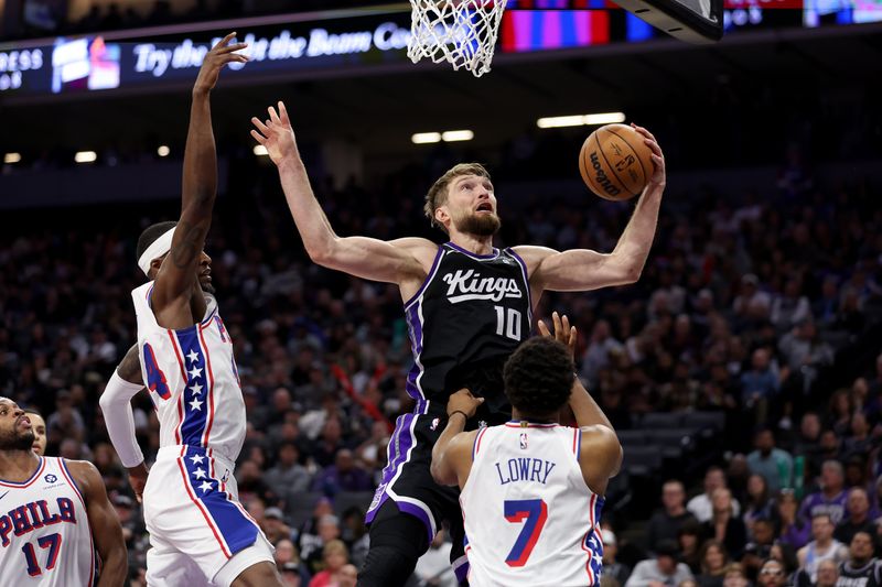 SACRAMENTO, CALIFORNIA - MARCH 25: Domantas Sabonis #10 of the Sacramento Kings goes for a rebound against Paul Reed #44 and Kyle Lowry #7 of the Philadelphia 76ers in the first half at Golden 1 Center on March 25, 2024 in Sacramento, California. NOTE TO USER: User expressly acknowledges and agrees that, by downloading and or using this photograph, User is consenting to the terms and conditions of the Getty Images License Agreement.  (Photo by Ezra Shaw/Getty Images)