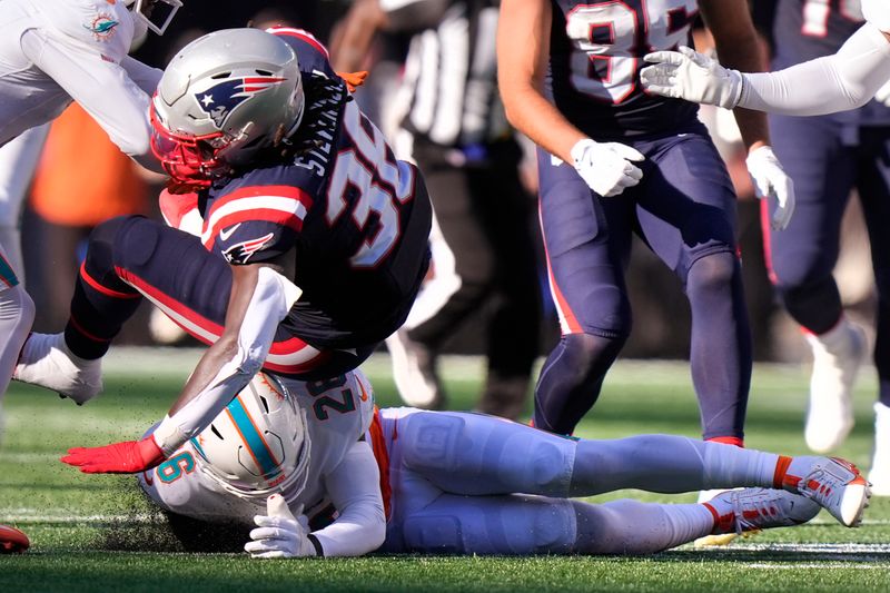 New England Patriots running back Rhamondre Stevenson (38) takes a low hit from Miami Dolphins safety Marcus Maye, bottom, during the second half of an NFL football game, Sunday, Oct. 6, 2024, in Foxborough, Mass. (AP Photo/Steven Senne)