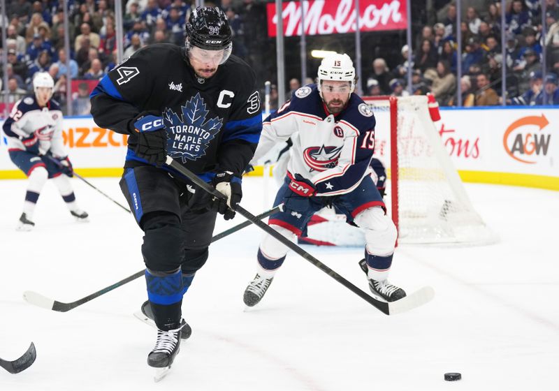 Jan 22, 2025; Toronto, Ontario, CAN; Toronto Maple Leafs center Auston Matthews (34) battles for the puck with Columbus Blue Jackets defenseman Dante Fabbro (15) during the third period at Scotiabank Arena. Mandatory Credit: Nick Turchiaro-Imagn Images