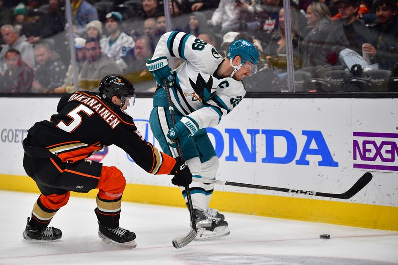 Jan 31, 2024; Anaheim, California, USA; Anaheim Ducks defenseman Urho Vaakanainen (5) plays for the puck against San Jose Sharks center Logan Couture (39) during the first period at Honda Center. Mandatory Credit: Gary A. Vasquez-USA TODAY Sports