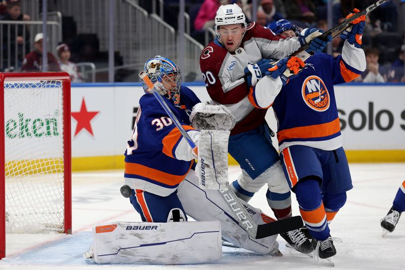Jan 28, 2025; Elmont, New York, USA; Colorado Avalanche center Ross Colton (20) fights for the puck against New York Islanders defenseman Scott Perunovich (26) and goaltender Ilya Sorokin (30) during the first period at UBS Arena. Mandatory Credit: Brad Penner-Imagn Images