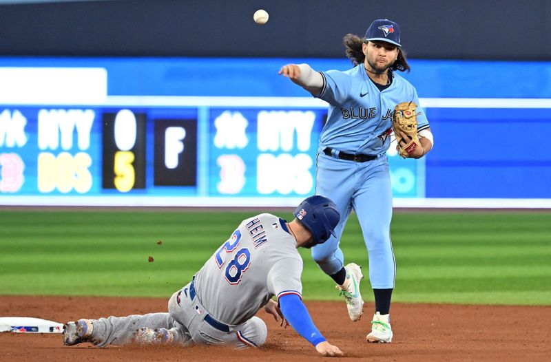 Sep 14, 2023; Toronto, Ontario, CAN;   Toronto Blue Jays shortstop Bo Bichette (11) throws to first base for a double play after forcing out Texas Rangers catcher Jonah Heim (28) at second base in the seventh inning at Rogers Centre. Mandatory Credit: Dan Hamilton-USA TODAY Sports