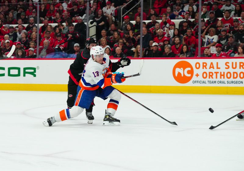 Apr 20, 2024; Raleigh, North Carolina, USA; New York Islanders center Mathew Barzal (13) gets the shot away against Carolina Hurricanes center Sebastian Aho (20) during the second period in game one of the first round of the 2024 Stanley Cup Playoffs at PNC Arena. Mandatory Credit: James Guillory-USA TODAY Sports