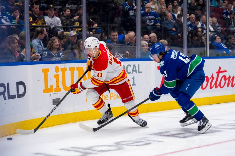 Nov 12, 2024; Vancouver, British Columbia, CAN; Vancouver Canucks defenseman Quinn Hughes (43) defends against Calgary Flames forward Mikael Backlund (11) during the first period at Rogers Arena. Mandatory Credit: Bob Frid-Imagn Images