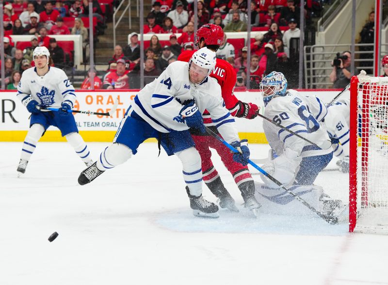 Apr 13, 2025; Raleigh, North Carolina, USA;  Toronto Maple Leafs defenseman Morgan Rielly (44) and goaltender Joseph Woll (60) watch the puck against Carolina Hurricanes center Jack Roslovic (96) during the third period at Lenovo Center. Mandatory Credit: James Guillory-Imagn Images