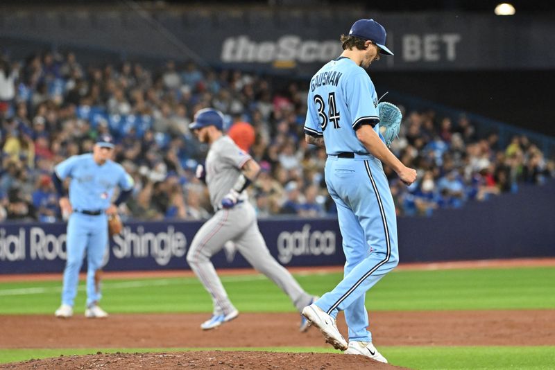 Sep 14, 2023; Toronto, Ontario, CAN;   Toronto Blue Jays pitcher Kevin Gausman (34 prepares for his next pitch as Texas Rangers catcher Jonah Heim (28) rounds the bases after hitting a solo home run in the third inning at Rogers Centre. Mandatory Credit: Dan Hamilton-USA TODAY Sports