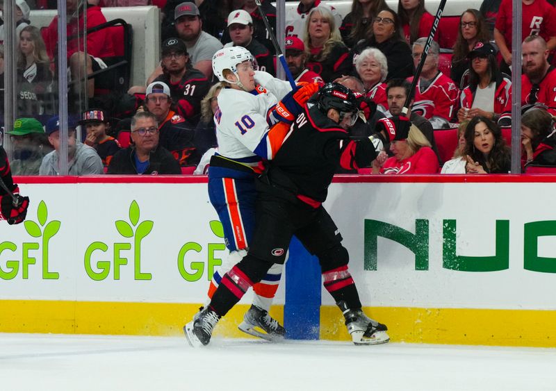 Apr 20, 2024; Raleigh, North Carolina, USA; Carolina Hurricanes defenseman Dmitry Orlov (7) checks New York Islanders right wing Simon Holmstrom (10) during the second period in game one of the first round of the 2024 Stanley Cup Playoffs at PNC Arena. Mandatory Credit: James Guillory-USA TODAY Sports