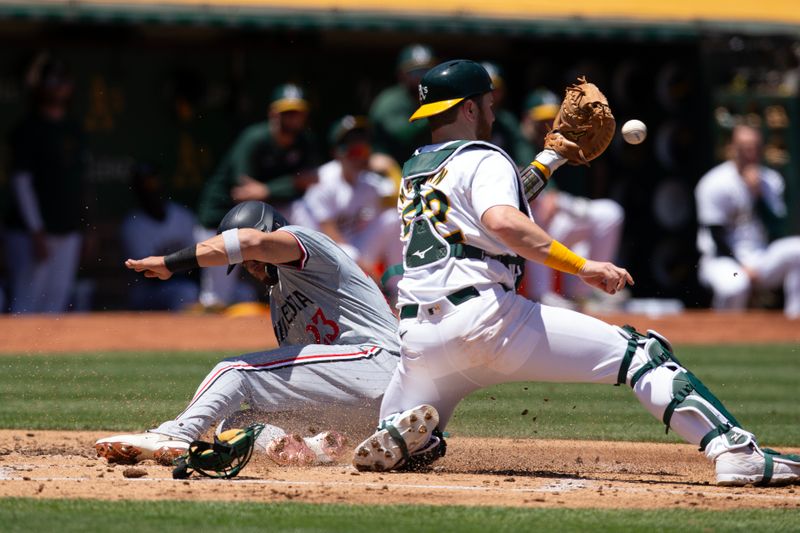 Jun 22, 2024; Oakland, California, USA; Minnesota Twins designated hitter Royce Lewis (23) slides safely home ahead of the tag by Oakland Athletics catcher Kyle McCann (52) during the second inning at Oakland-Alameda County Coliseum. Mandatory Credit: D. Ross Cameron-USA TODAY Sports