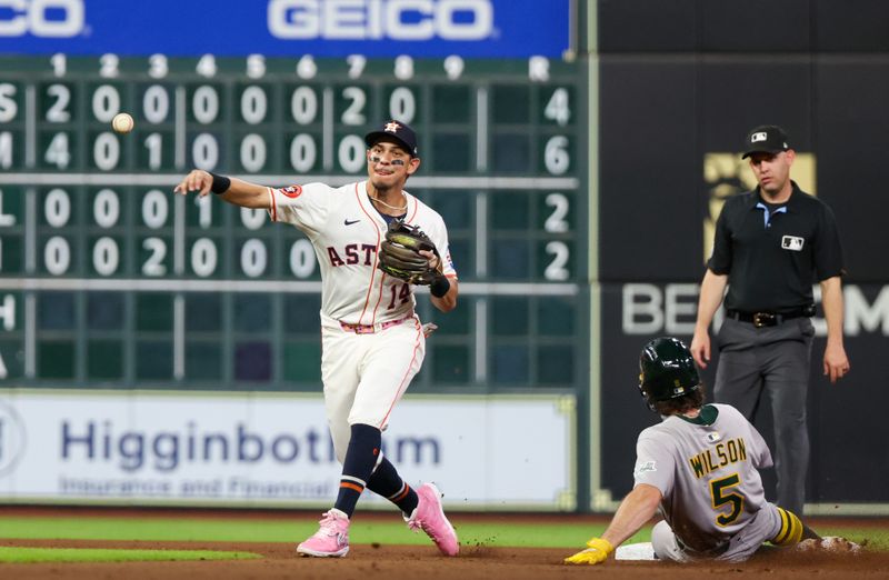 May 27, 2025; Houston, Texas, USA; Houston Astros second baseman Mauricio Dubon (14) turns the double play over Athletics shortstop Jacob Wilson (5) in the sixth inning at Daikin Park. Mandatory Credit: Thomas Shea-Imagn Images
