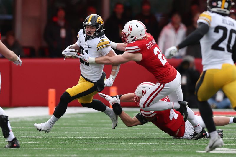 Nov 24, 2023; Lincoln, Nebraska, USA; Iowa Hawkeyes wide receiver Kaden Wetjen (21) is tackled by Nebraska Cornhuskers defensive back Isaac Gifford (2) at Memorial Stadium. Mandatory Credit: Reese Strickland-USA TODAY Sports