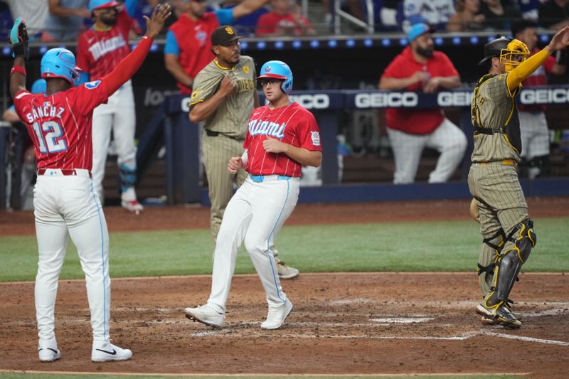 Aug 10, 2024; Miami, Florida, USA;  Miami Marlins designated hitter Jesús Sánchez (12) and first baseman Jonah Bride (41) score runs in the fifth inning against the San Diego Padres at loanDepot Park. Mandatory Credit: Jim Rassol-USA TODAY Sports