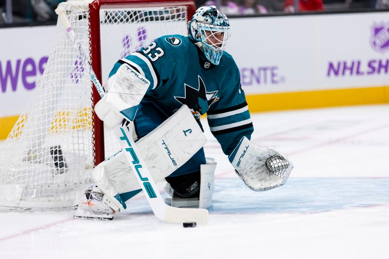 Nov 2, 2025; San Jose, California, USA;  San Jose Sharks goaltender Alex Nedeljkovic (33) deflects the puck against the Detroit Red Wings during the first period at SAP Center at San Jose. Mandatory Credit: John Hefti-Imagn Images