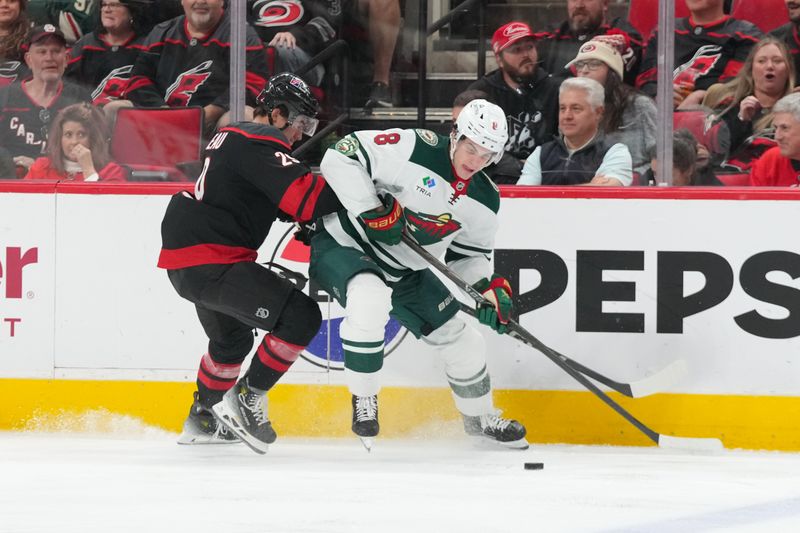 Nov 6, 2025; Raleigh, North Carolina, USA;  Minnesota Wild defenseman Zeev Buium (8) tries to control the puck against Carolina Hurricanes left wing Bradly Nadeau (29) during the first period at Lenovo Center. Mandatory Credit: James Guillory-Imagn Images