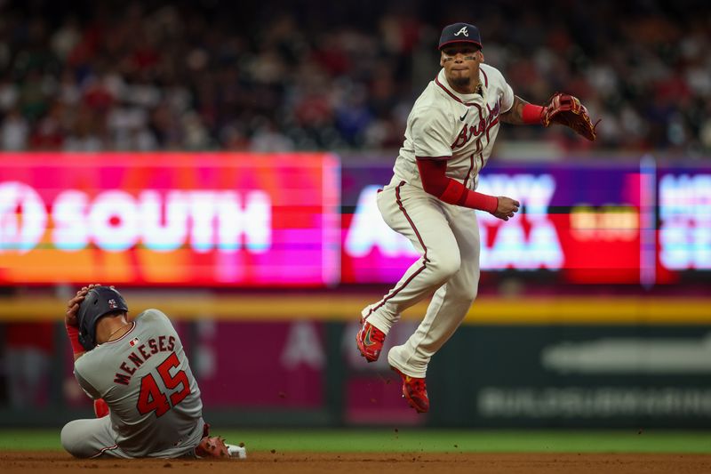 May 28, 2024; Atlanta, Georgia, USA; Atlanta Braves shortstop Orlando Arcia (11) turns a double play over Washington Nationals first baseman Joey Meneses (45) in the seventh inning at Truist Park. Mandatory Credit: Brett Davis-USA TODAY Sports
