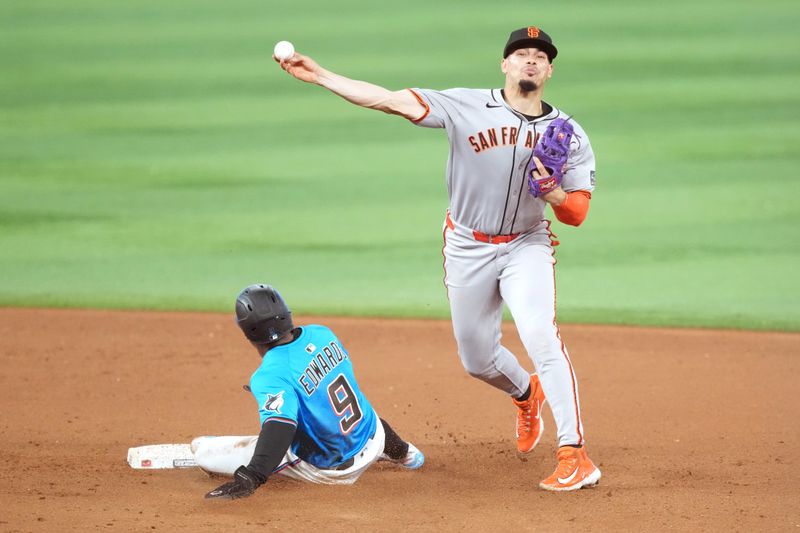 Jun 1, 2025; Miami, Florida, USA;  San Francisco Giants shortstop Willy Adames (2) turns a double play in the ninth inning as Miami Marlins short stop Xavier Edwards (9) slides into second base at loanDepot Park. Mandatory Credit: Jim Rassol-Imagn Images