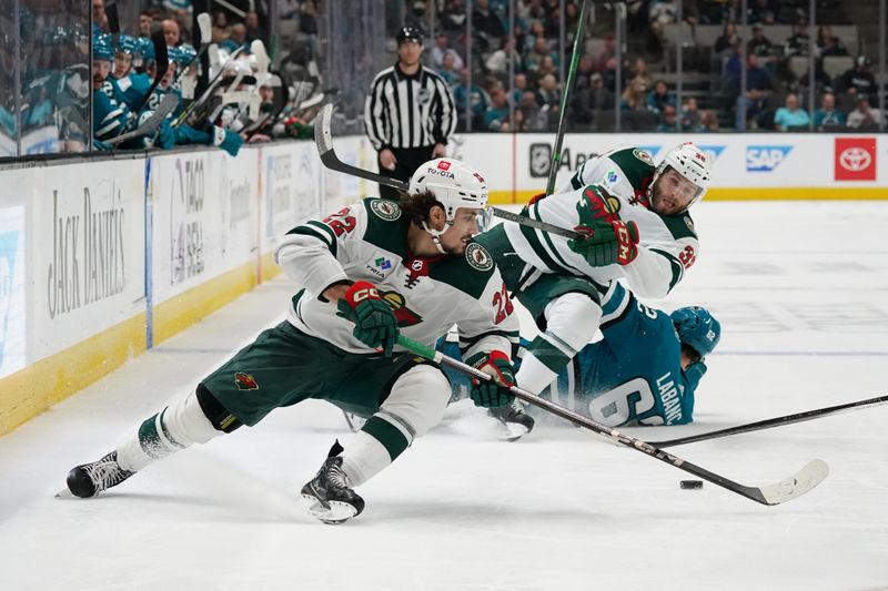 Apr 13, 2024; San Jose, California, USA; Minnesota Wild center Marat Khusnutdinov (22) controls the puck as Minnesota Wild right wing Ryan Hartman (38) collides with San Jose Sharks right wing Kevin Labanc (62) during the third period at SAP Center at San Jose. Mandatory Credit: David Gonzales-USA TODAY Sports