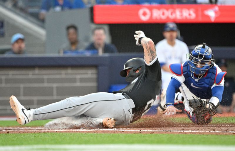 May 21, 2024; Toronto, Ontario, CAN;  Chicago White Sox catcher Korey Lee (26) slides home to score a run ahead of a tag from Toronto Blue Jays catcher Danny Jansen (9) in the second inning at Rogers Centre. Mandatory Credit: Dan Hamilton-USA TODAY Sports