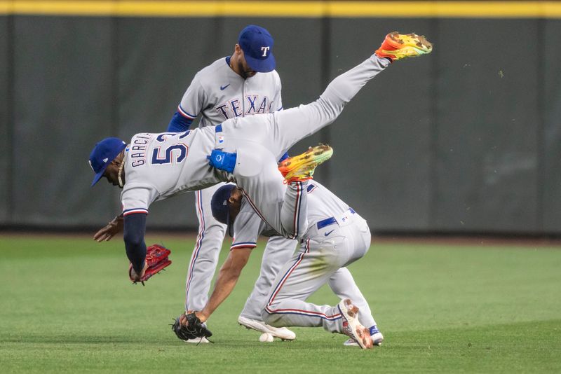 Sep 30, 2023; Seattle, Washington, USA; Texas Rangers right fielder Adolis Garcia (53) collides with second baseman Marcus Semien (2), lower right, on a ball hit by Seattle Mariners shortstop J.P. Crawford (3) whiel centerfielder Leody Taveras (3) watches during the fifth inning at T-Mobile Park. Mandatory Credit: Stephen Brashear-USA TODAY Sports