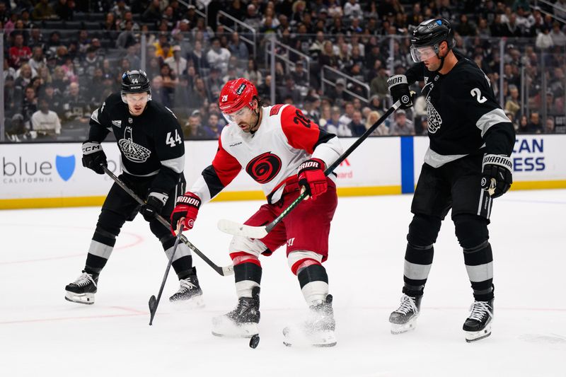 Oct 18, 2025; Los Angeles, California, USA; Carolina Hurricanes left wing William Carrier (28) holds on to Los Angeles Kings defenseman Brian Dumoulin (2), right, stick during the third period at Crypto.com Arena. Mandatory Credit: William Liang-Imagn Images